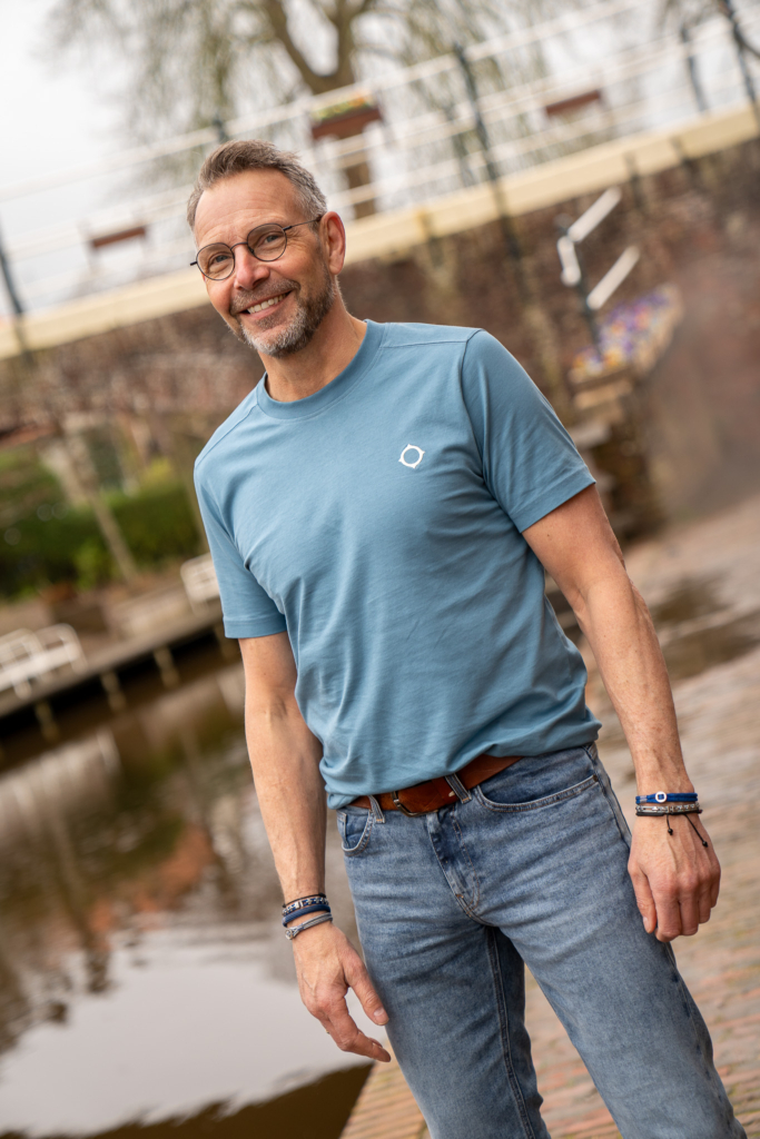 man lacht met een mid blue t-shirt van Ma-Strum, effen t-shirt, klein logo in lichtblauw op borst,