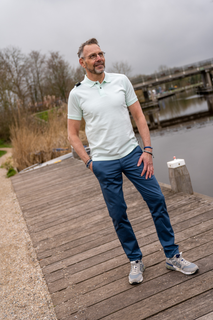 man aan de kade van het Winsumerdiep in Winsum, duurzame herenkleding te koop bij Sytha, MUD jeans chino slimfit pasvorm, sneakers Premiata