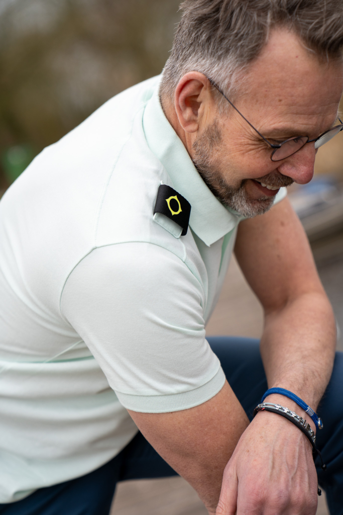man kijkend naar beneden met lichtgroene mintkleur polo van Ma-Strum, zwart met wit logo op schouder, exlusieve herenmode in Winsum