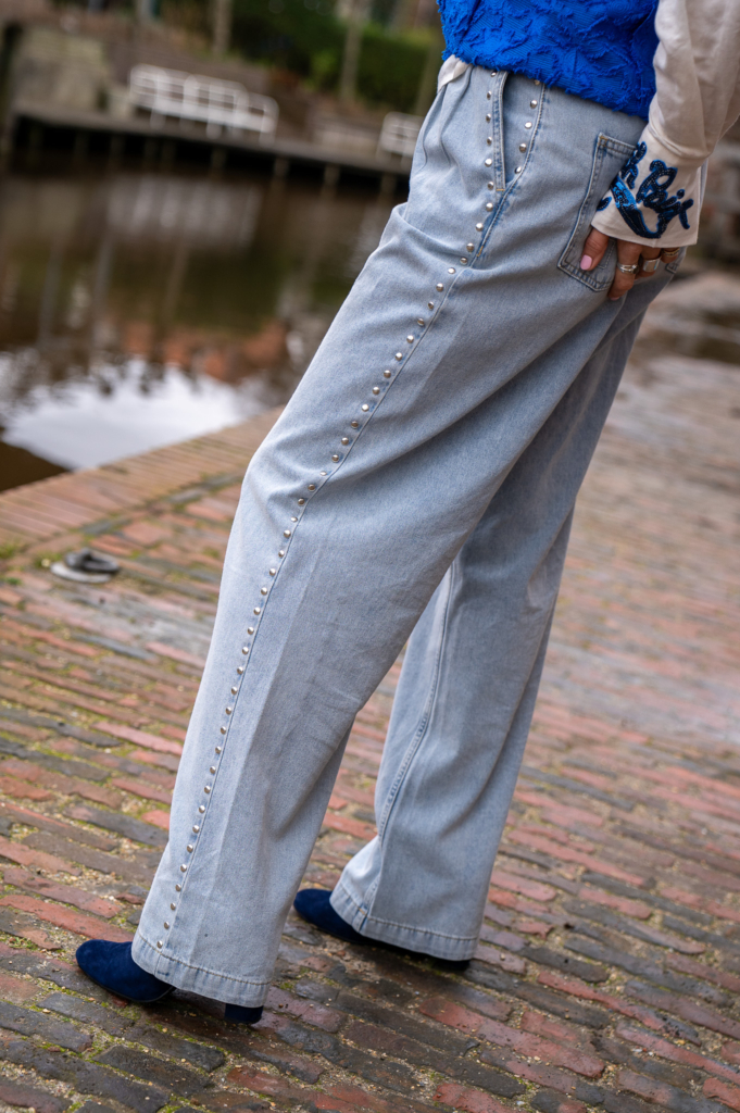 zijkant van een licht jeans van POM Amsterdam met verticale zilveren studs aan de zijkant