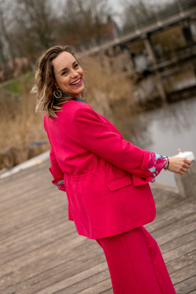 Sytha jr draait vrolijk rond op de kade van Winsum in een rose middellange blazer van POM Amsterdam